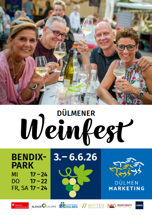 Fünf Personen sitzen lächelnd mit Weißwein und bunt gekleideten Outfits am Tisch